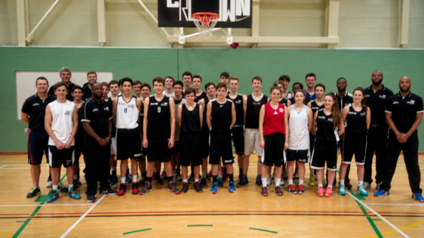 Team and coaches posing together on an indoor basketball court